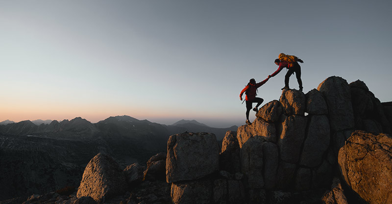 sparing-partner Bergsteiger helfen einander auf einem Felsen